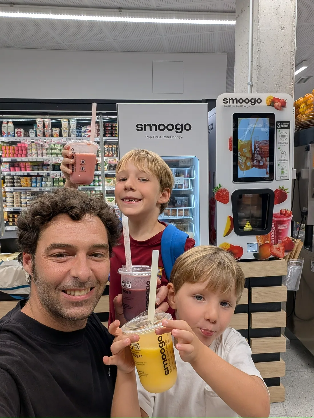 Padre y sus dos hijos con smoothies SMOOGO en el supermercado