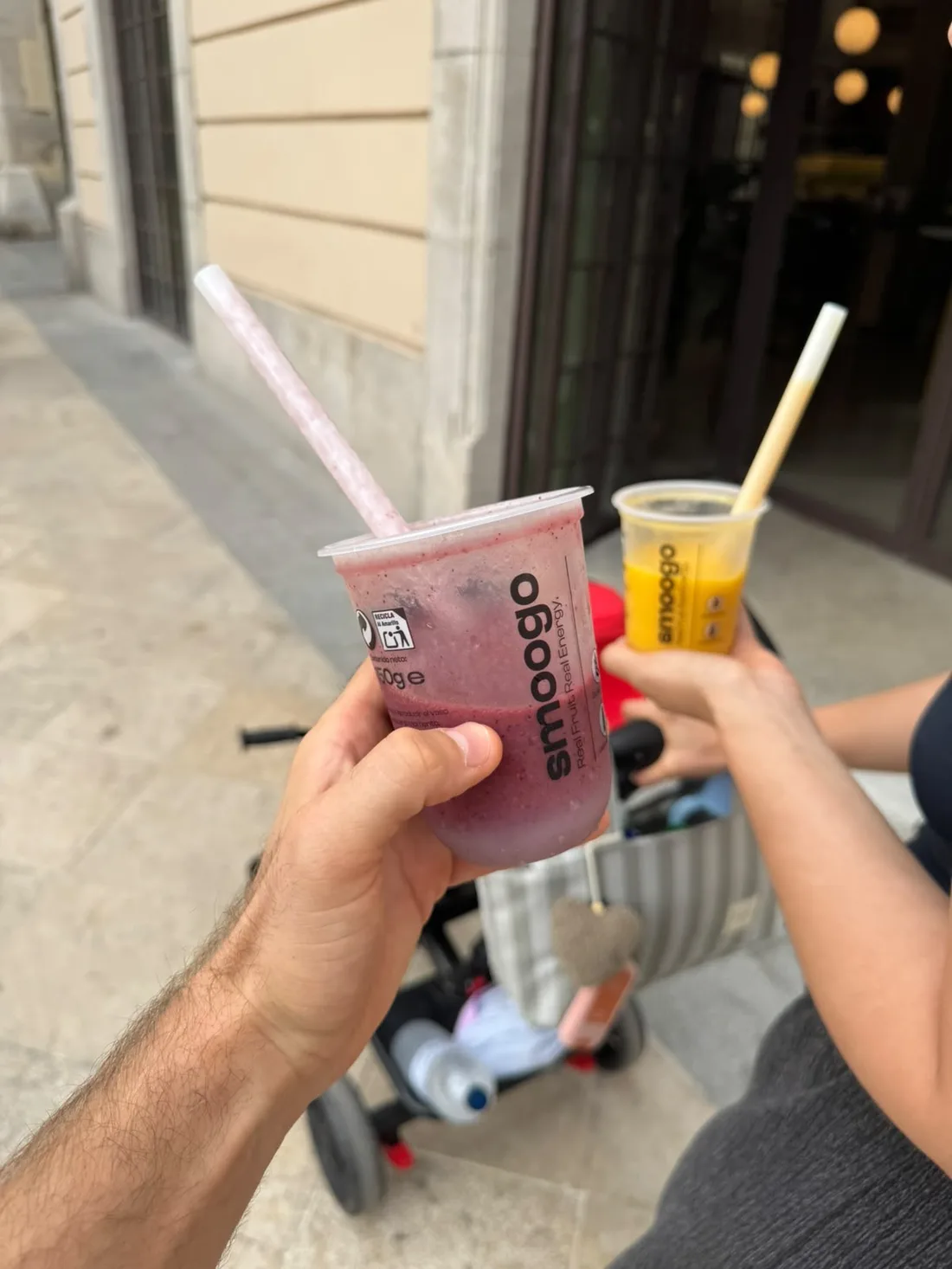 Dos clientes brindando con sus smoothies SMOOGO en la calle